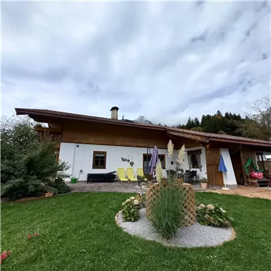 Ein charmantes Haus mit einem gepflegten Garten und bunten Blumen. Die Terrasse ist mit Liegestühlen und Sonnenschirmen ausgestattet.