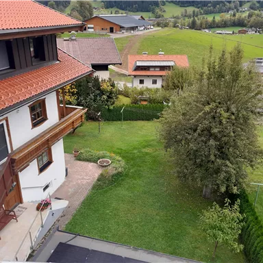 A quiet landscape with several houses and well-maintained gardens. In the background, green meadows and gentle hills can be seen.