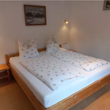 Ein gemütliches Schlafzimmer mit einem großen Doppelbett und zwei Nachttischen. Die Wände sind hell und es gibt sanfte Beleuchtung.