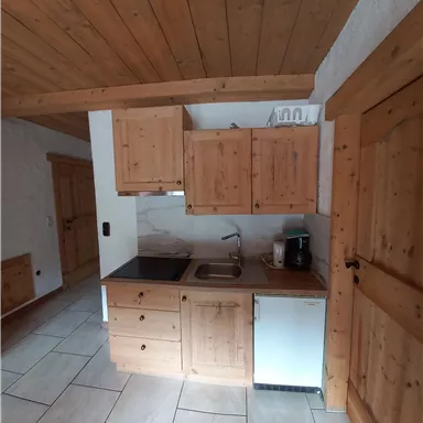 Eine gemütliche Küche aus Holz mit modernen Geräten. Der Raum hat helle Fliesen und eine einladende Atmosphäre.