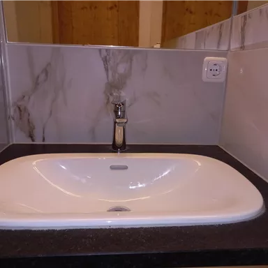 Ein modernes Waschbecken auf einer dunklen Ablage mit eleganten Wänden. Der Wasserhahn ist aus glänzendem Metall.