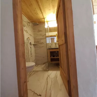 Ein modernes Badezimmer mit marmorierten Wänden und einem Holzrahmen. Das Licht ist warm und sorgt für eine einladende Atmosphäre.