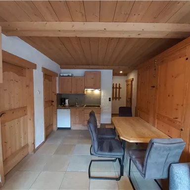 Eine gemütliche Küche mit einem Esstisch und modernen Stühlen. Die Wände sind aus hellem Holz, was eine warme Atmosphäre schafft.