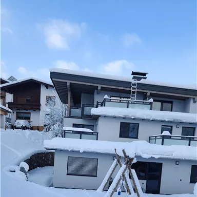 Ein modernes Gebäude mit mehreren Etagen, umgeben von einer dicken Schneeschicht. Der Himmel ist klar und blau, was eine ruhige Winteratmosphäre schafft.