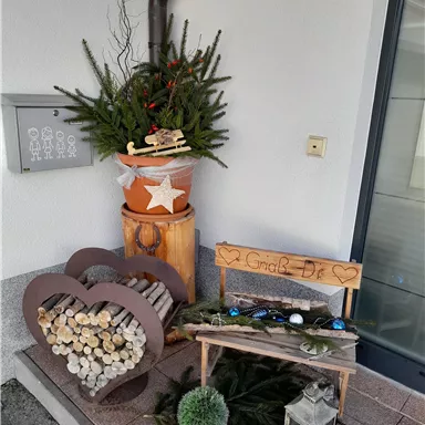A decorative entrance area with wooden logs, a cozy bench, and a plant bowl with pine branches. An inviting atmosphere with rustic charm.