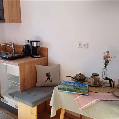 Eine gemütliche Küche mit Holzdetails und einem kleinen Tisch. Der Tisch ist mit Geschirr und einer Blumenvase dekoriert.