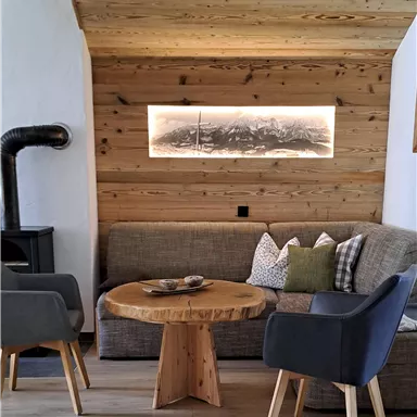 A cozy living area with modern furniture and wooden paneling. The round wooden table complements the relaxed atmosphere.