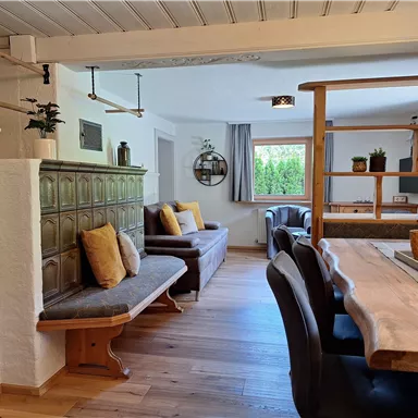 A cozy living space with wooden floors and stylish furnishings. On the left side, there is a stove, and there is a large dining table group.