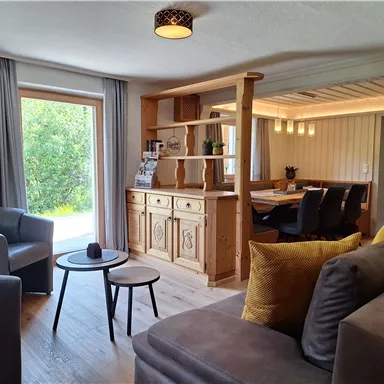 A cozy living room with modern furniture and natural light. The wooden details add a rustic charm to the atmosphere.