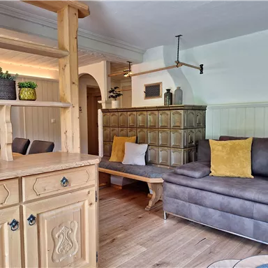 A cozy living space with a gray sofa and decorative cushions. The room features wooden details and a pleasant, inviting atmosphere.