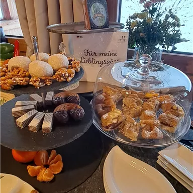 A lovingly decorated table with various delicacies. Cookies, cakes, and snacks are beautifully arranged and invite you to enjoy.