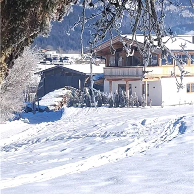 A snowy landscape with a view of some houses. The sky is blue and the surroundings are quiet.