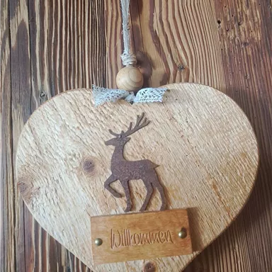 A heart-shaped wooden plaque with a deer motif and the inscription "Waldheim". It hangs on a natural thread.