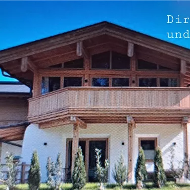 A modern wooden house in the mountains with a clear blue sky. The facade is inviting and surrounded by green landscape.