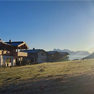 A picturesque mountain landscape with houses and a warm sun in the background. The clear air and tranquil atmosphere invite relaxation.