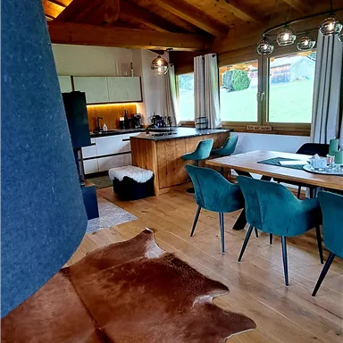 A modern, inviting dining room with a wooden beam ceiling. Stylish furniture and a cowhide create a cozy atmosphere.