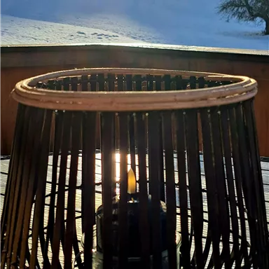 A candle in a decorative basket is in the foreground. In the background, there are snow-covered hills and the sun is shining brightly.