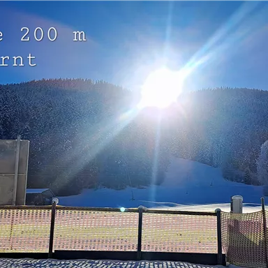 A clear blue sky above a snowy slope. The ski school is 200 m away.