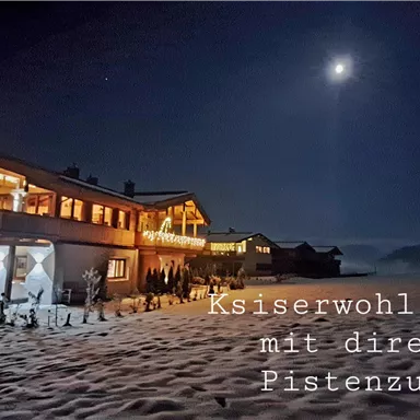 A cozy chalet in winter, surrounded by snow and illuminated by a clear moon. The chalet offers direct access to the slopes.