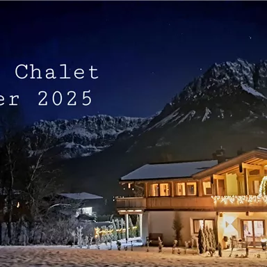 A picturesque chalet in the mountains, surrounded by snow. The night sky is clear and the lights of the chalet shine invitingly.