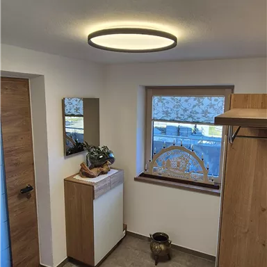 A bright hallway with modern furniture and a large window. The walls are painted light and there is a pleasant atmosphere.