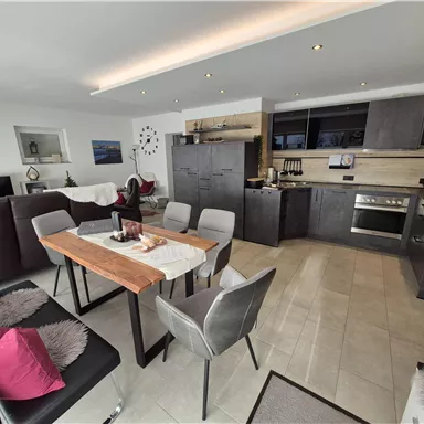 A modern apartment with an open kitchen and dining area. The space is bright and spacious, with elegant furniture and decorative accents.