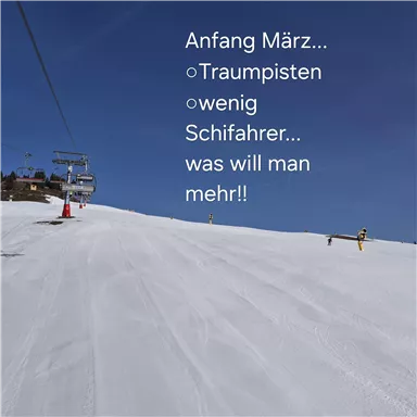 Ein malerischer Skihang im Frühling mit perfektem Schnee und klar blauem Himmel. Nur wenige Skifahrer genießen die traumhaften Pisten.