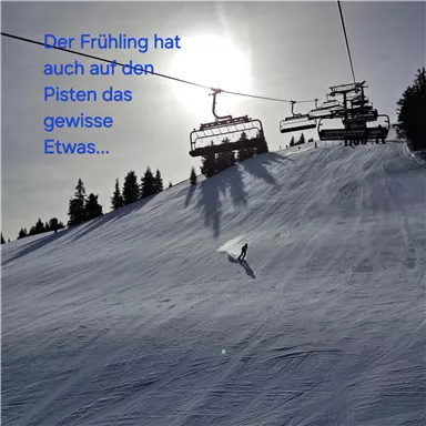 Eine schneebedeckte Piste im Frühling mit einer Skifahrerin. Im Hintergrund sind Skilifte und ein klarer Himmel zu sehen.