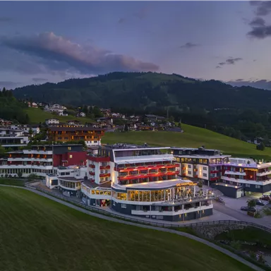 A modern hotel in a picturesque landscape with gentle hills. The buildings are a blend of traditional and contemporary architecture.