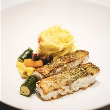 A plate with fried fish, served with pasta and colorful vegetables. The dish looks appetizing and fresh.