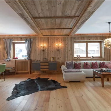 A modern living room with wooden walls and a warm, inviting atmosphere. Cozy furniture and a beautiful rug create a relaxed ambiance.