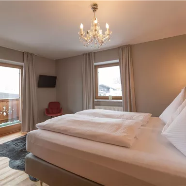 A cozy bedroom with two comfortable beds and modern furniture. Large windows let in plenty of light and offer a beautiful view.