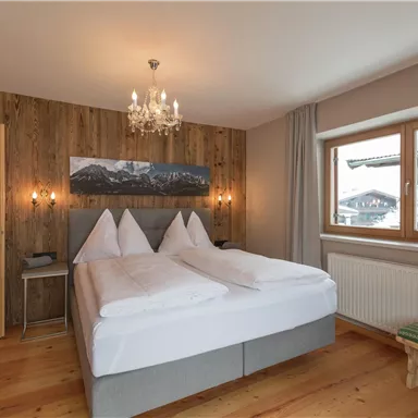 A cozy double room with wood paneling and a large window. The atmosphere is warm and inviting, perfect for relaxation.