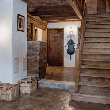 Ein einladender Flur mit Holzverkleidung und einer Treppe. Korb-Organizer und Wandleuchten schaffen eine gemütliche Atmosphäre.