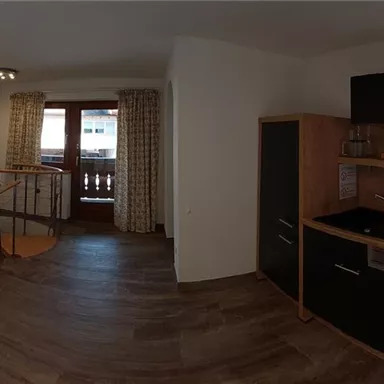 Ein gemütliches Wohnzimmer mit einer modernen Küche und einem Esstisch. Die Einrichtung ist hell und einladend, mit Holz- und neutralen Farbtönen.