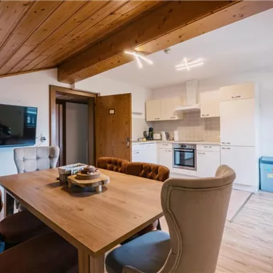 Eine moderne Küche mit einem Essbereich und einem Holztisch. Der Raum ist hell und gemütlich gestaltet.