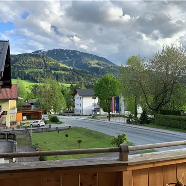 A picturesque landscape with green hills and a quiet road. In the background, mountains and clouds can be seen.