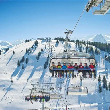 Eine Skiliftfahrt über schneebedeckte Berge. Die Passagiere genießen die Aussicht auf die winterliche Landschaft.