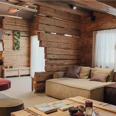 Ein moderner Wohnbereich mit Holzverkleidung und gemütlichen Sofas. Große Fenster lassen viel Licht herein und verleihen dem Raum eine einladende Atmosphäre.