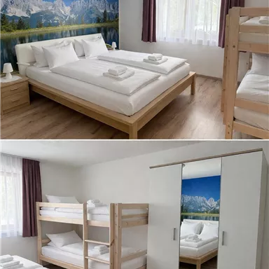 A bright room with two beds and a bunk bed. The wall is decorated with a mountain picture and there are large windows for plenty of daylight.