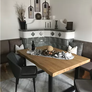 A cozy dining area with a rectangular wooden table and modern chairs. The walls are painted in neutral colors, and the lighting is accentuated by subtle pendant lights.