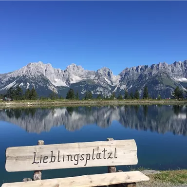 An idyllic mountain landscape with clear bodies of water and a view of majestic peaks. In the foreground, there is a bench with the inscription "Favorite Place."