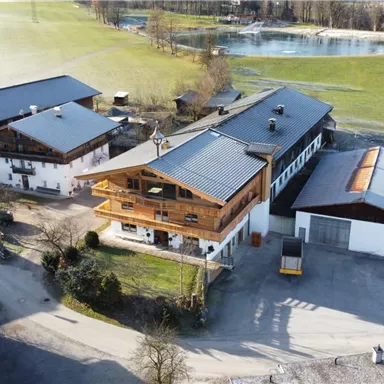 A traditional building surrounded by rural landscape. Gentle hills and a calm area in the background.