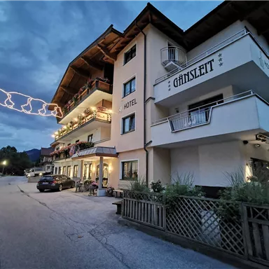 Ein gemütliches Hotel mit dem Namen "Günisleith" in einer ruhigen Umgebung. Der Himmel ist bewölkt und die Lichter sorgen für eine besondere Atmosphäre.