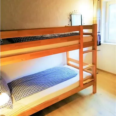 A simple bedroom with a bunk bed. There is a window that lets in natural light.