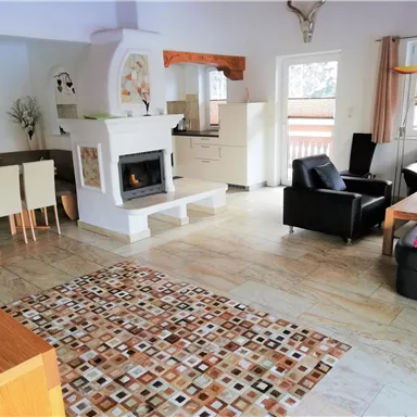 A modern living room with a comfortable sofa and a dining table. The fireplace creates a cozy atmosphere.