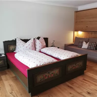 A cozy bedroom with a large double bed and a modern seating area. The room features beautiful wooden details and an inviting atmosphere.