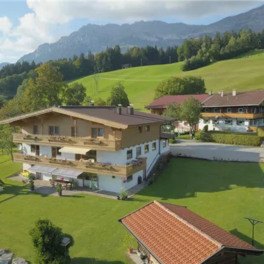 A picturesque country house surrounded by green meadows and mountains. The property features a beautiful garden with a playground and views of nature.