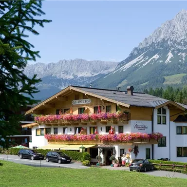 Ein charmantes Hotel mit blühenden Balkonen inmitten einer bergigen Landschaft. Umgeben von grünen Wiesen und majestätischen Bergen.