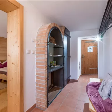 Ein gemütlicher Flur mit einem Backsteingestell und einem kleinen Sitzecke. Die Wände sind hell und der Boden ist gefliest.